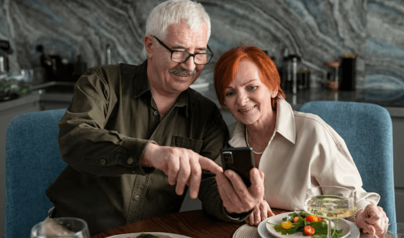 Older couple looking at a phone together over lunch